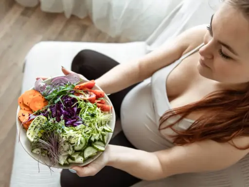 Kobieta w ciąży delektuje się zdrową sałatką, dbając o dietę w ciąży. Kolorowe warzywa to podstawa.