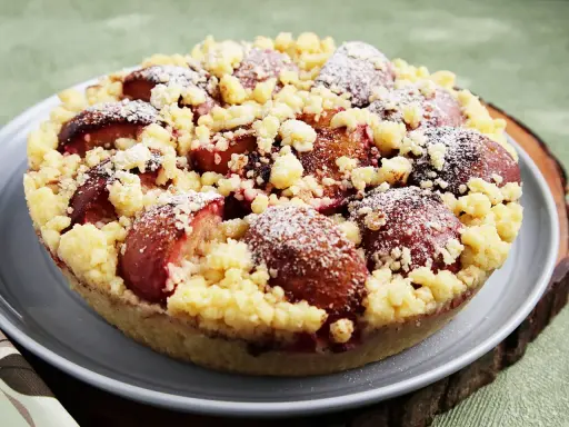 Ein köstlicher pflaumenkuchen ohne hefeteig, bestreut mit Puderzucker und knusprigen Streuseln.