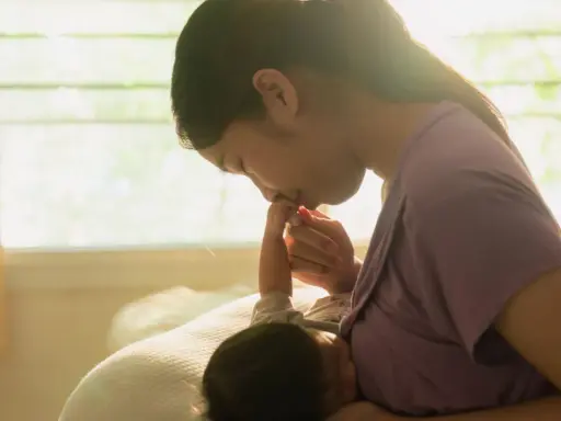 Dolce momento tra madre e neonato. La mamma bacia la manina del piccolo, attenta ai suoi segnali fame.