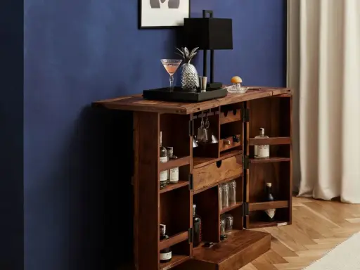 Elegante mobile bar design in legno scuro, aperto, con bottiglie, bicchieri, lampada e decorazioni.