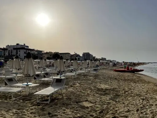 Spiaggia di Igea Marina con lettini e ombrelloni chiusi, bagnino pronto con la sua imbarcazione sul mare calmo.