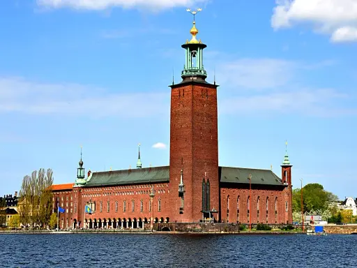 Stockholms stadshus reser sig stolt vid vattnet, dess ikoniska torn dominerar horisonten.