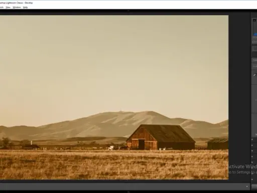 Paisaje rural con granero y montañas, con un filtro sepia aplicado en Photoshop para un estilo vintage.
