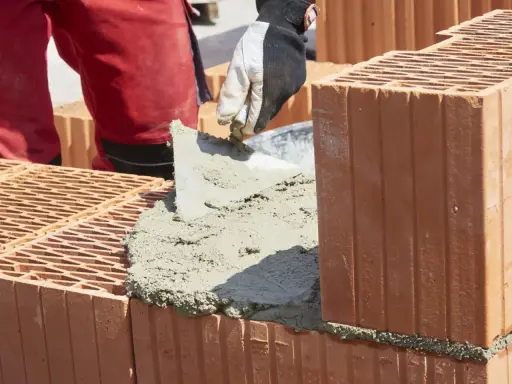 Budowanie muru z pustaków ceramicznych, nakładanie zaprawy. Właśnie tak jak zrobic cement do budowy.