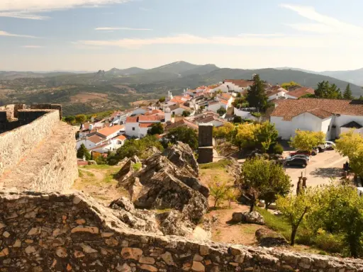 Blick auf das malerische Dorf Portalegre mit seinen weißen Häusern und roten Dächern, umgeben von einer alten Steinmauer und bergiger Landschaft.