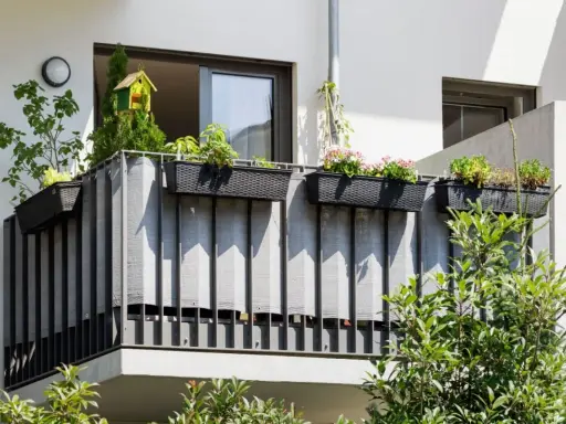 Balcone condominio con fioriere e telo grigio per creare idee privacy. Un nido per uccelli decora la vegetazione.