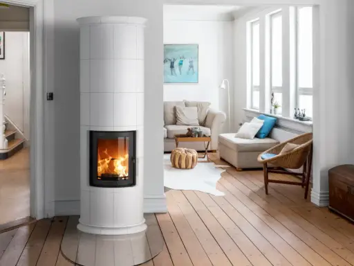 Un élégant poêle de masse blanc diffuse une douce chaleur dans un salon lumineux aux planchers de bois.