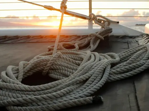Coup de soleil sur un bateau, une corde épaisse est prête à faire un noeud de marin.