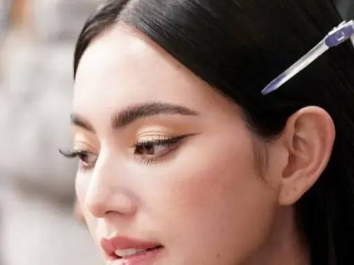 Primer plano de una mujer con ojos rasgados, delineado de gato y cabello oscuro recogido con una pinza.