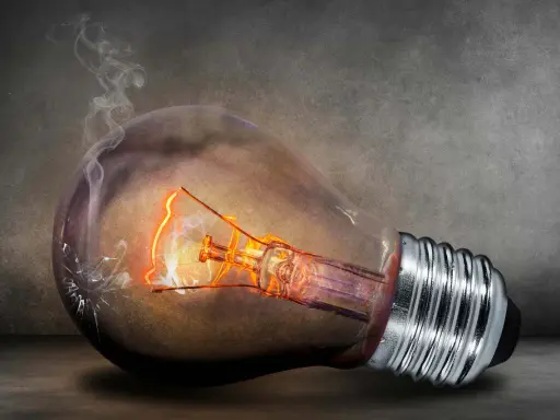 En glödlampa med glödande tråd och rök som stiger från en spricka. Kanske en symbol för högt elpris nattetid.