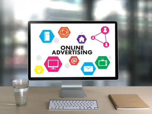 Komputer z hasłem "ONLINE ADVERTISING" i ikonami symbolizującymi różne formy reklamy online. Ciekawa reklama!