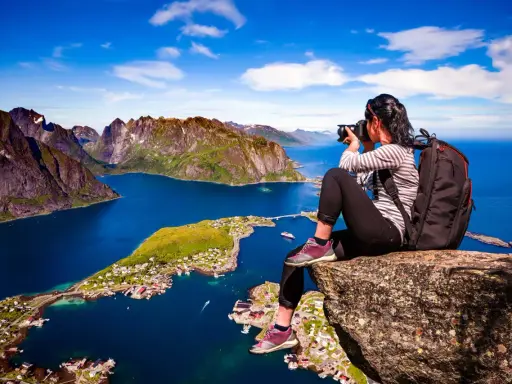 En fotograf fångar de dramatiska vyerna över Lofoten sevärdheter, med branta berg och en idyllisk by vid det blå havet.