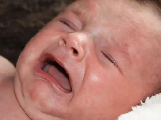 Ett kolikbarn gråter intensivt, med ögonen slutna och munnen öppen.
