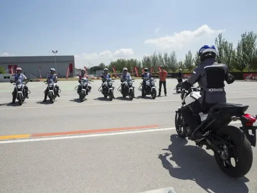 Grupo de motoristas en formación, listos para practicar con sus motos carmet a1 en un circuito.