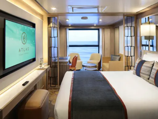 Interni lussuosi di una cabina garantita Costa Crociere con letto comodo, divanetti, scrivania e TV. Vista mare dalla finestra.