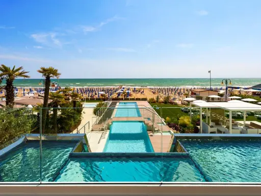 Lido di Jesolo atrakcje: baseny z widokiem na plażę, palmy i morze. Idealne miejsce na wakacje.