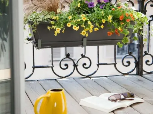 Jardinière extérieure fleurie sur un balcon, une belle idée composition pour un coin lecture avec un livre et des lunettes.