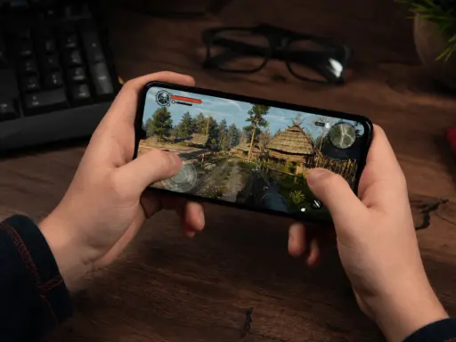 Ręce trzymają smartfon z grą akcji w stylu fantasy. To jedna z najlepszych gier mobilnych.
