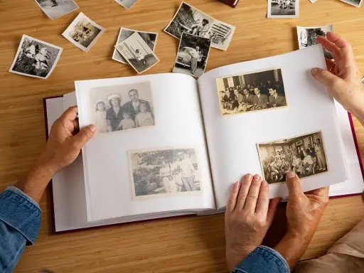 Manos hojeando un álbum de fotos antiguas, reviviendo recuerdos. Quizás buscando frases 50 aniversario para acompañar estas imágenes.