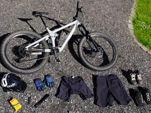 Fullt utrustad för en dag på stigarna: en grå heldämpad cykel, hjälm, handskar, shorts, skor och skydd. Allt för din mtb utrustning.
