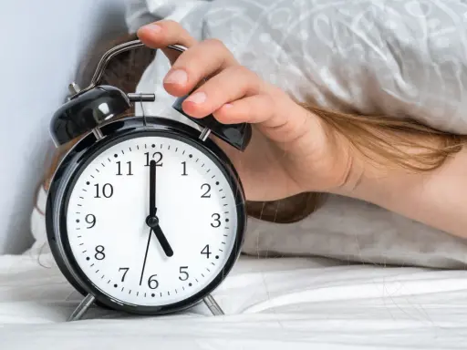 Ręka wyłącza budzik. Jest 5:00, a 0303 znaczenie tego czasu to nowy początek dnia.