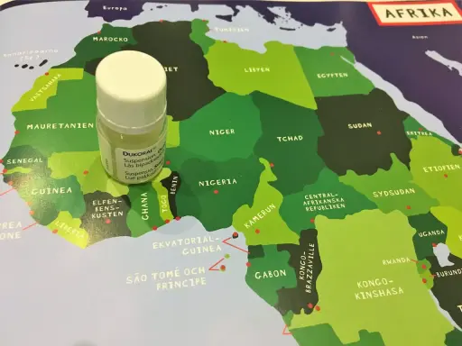 En liten flaska Dukoral® står på en karta över Afrika, nära Guinea och Elfenbenskusten.