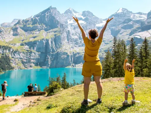Familia disfrutando de un día en la suiza con niños, con un lago turquesa y montañas imponentes de fondo.