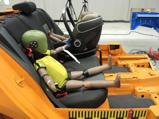 Maniquíes en un asiento de coche de prueba, preparándose para un test de seguridad según la normativa ECE R44/04.