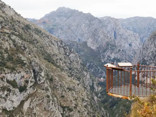 Mirador en la ruta del desfiladero de la Hermida, con imponentes montañas y un balcón de metal oxidado.