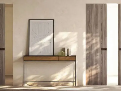 Porta in cartongesso con finitura in legno, minimalista e moderna, con un quadro astratto appeso sopra un tavolino.
