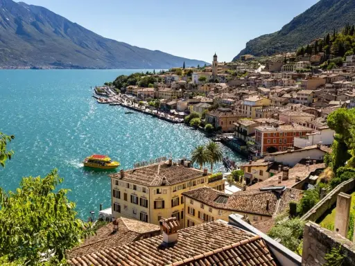 Limone sul Garda cosa vedere: pittoresca cittadina sul lago, con case colorate, un battello giallo e montagne sullo sfondo.
