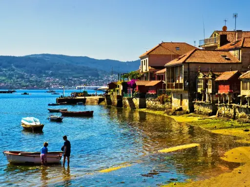 Un pueblo costero gallego, con barcas en el agua y casas de piedra, uno de los pueblos mas bonitos de Galicia.