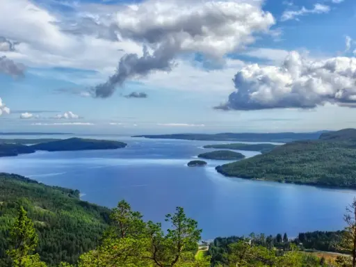 Vacker utsikt över en sjö med öar, omgiven av skogklädda berg. Ett perfekt ställe att uppleva Stockholms naturreservat.