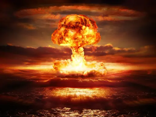Potężny grzyb atomowy nad oceanem. Widoczne przerażające skutki bomby jądrowej: fala uderzeniowa, ogień i dym.