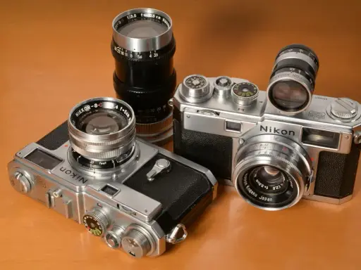 Kolekcja aparatów Nikon z obiektywami. Dwa modele Nikon z lat 50. i 60. XX wieku, każdy z innym obiektywem Nikkor.
