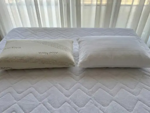 Dos almohadas sobre un colchón: una de fibra con Aloe Vera y otra viscoelástica. ¿Qué es mejor almohada de fibra o viscoelástica?