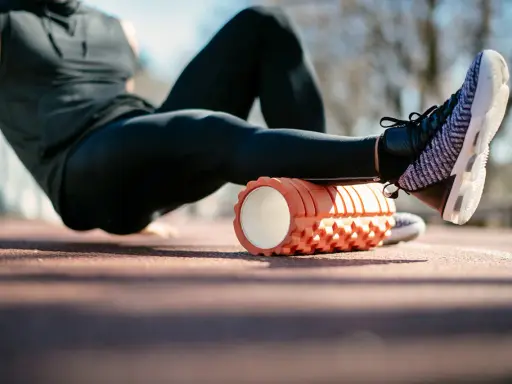 Sportler nutzt eine Faszienrolle vor oder nach dem Training zur Regeneration der Beinmuskulatur.