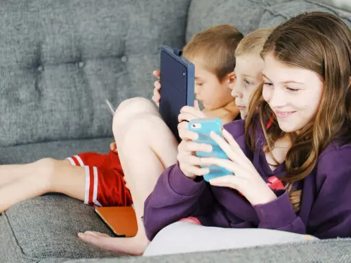 Trois enfants absorbés par leurs écrans, un rappel pour un atelier sensibilisation aux écrans.