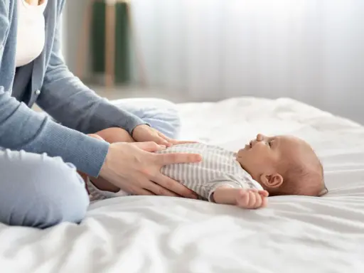 Mama masuje brzuszek niemowlaka, łagodząc bulgotanie w brzuchu i bolesne gazy.