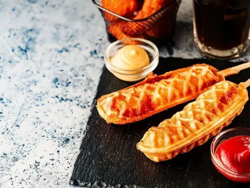 Pyszny corn dog przepis na patyku, podany z ketchupem i musztardą. Idealna przekąska!