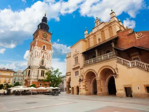 Wieża ratuszowa Kraków na Rynku Głównym, obok Sukiennic. Słoneczny dzień, błękitne niebo z chmurami.