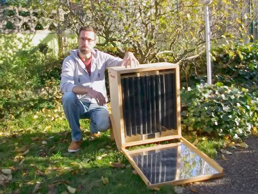 Un homme présente un séchoir solaire plan, un appareil ingénieux pour sécher des aliments grâce à l'énergie du soleil.