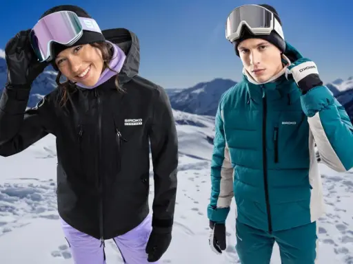 Para narciarzy w górach. Ona w czarnej kurtce hardshell, on w turkusowej kurtce softshell.