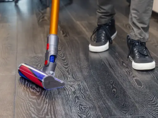 Aspiradora moderna limpia suelo vinílico con acabado de madera. Paso a paso, como limpiar suelo vinilico para un hogar impecable.