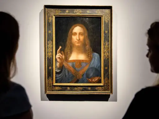 Two viewers admire Leonardo da Vinci's "Salvator Mundi," the most expensive piece of art ever sold, in its ornate frame.