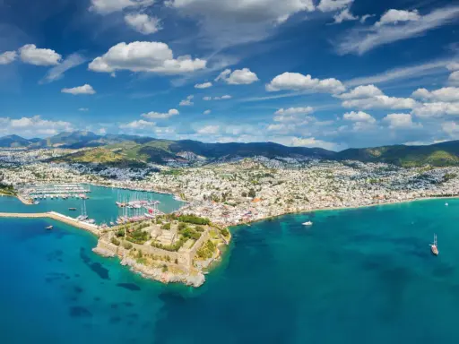 Widok na zamek i zatokę pełną łodzi. Czy to Bodrum, czy Alanya? Piękne turkusowe morze i białe domy na wzgórzach.