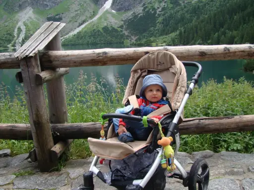 Niemowlak w wózku podziwia Tatry. Piękny widok na jezioro i góry.