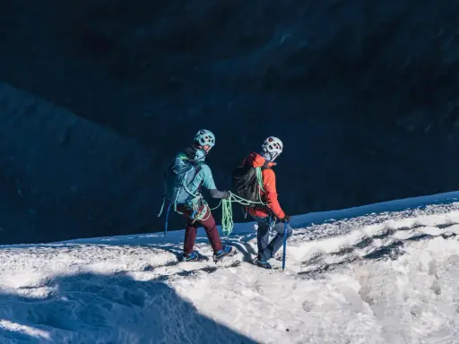 Dwóch alpinistów z raki i czekanami na lodowcu, przygotowuje się do wspinaczki.