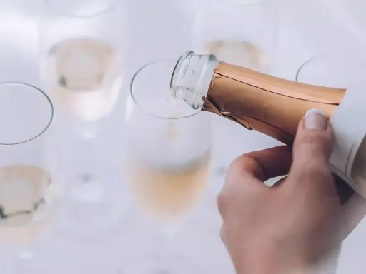 Eine Hand gießt Champagner in ein Glas. Die Bläschen steigen auf und lassen erahnen, wie gut der Champagner schmeckt.