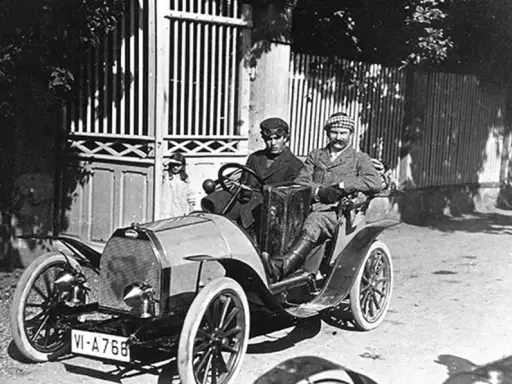 Zwei Männer in einem Bugatti, der aus Molsheim stammt, fahren durch eine sonnige Straße.